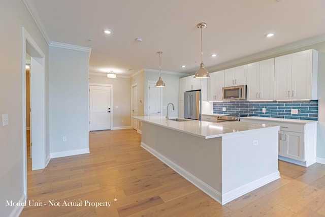 kitchen featuring stainless steel appliances, sink, light hardwood / wood-style flooring, white cabinets, and an island with sink