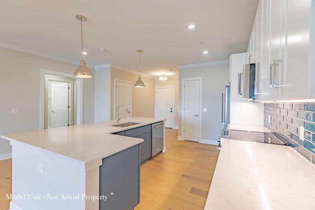 kitchen with sink, appliances with stainless steel finishes, decorative light fixtures, light hardwood / wood-style floors, and white cabinetry