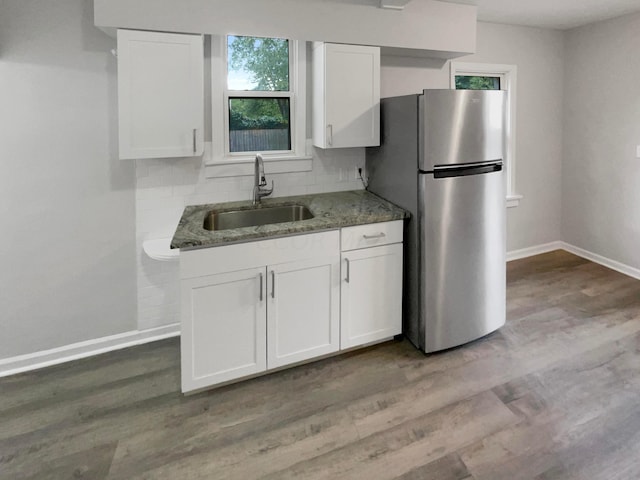 kitchen with light wood-type flooring, sink, stone counters, white cabinetry, and stainless steel refrigerator