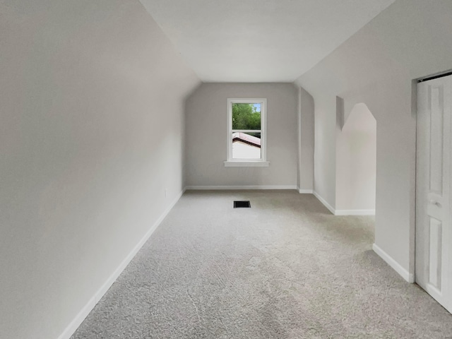 additional living space with light colored carpet and vaulted ceiling