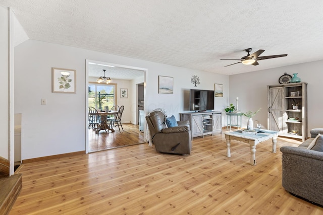 living room with ceiling fan, a textured ceiling, and light hardwood / wood-style flooring