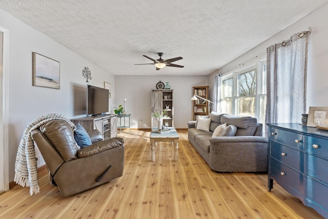 living room featuring ceiling fan, light hardwood / wood-style floors, and a textured ceiling