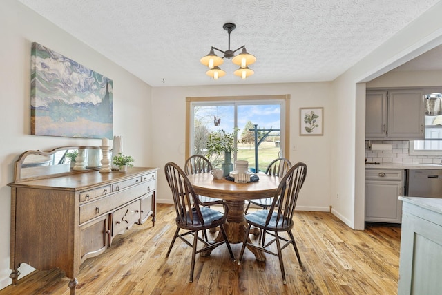 dining room with a notable chandelier, light hardwood / wood-style floors, and a textured ceiling