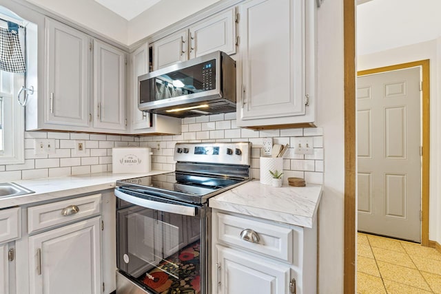 kitchen with white cabinetry, backsplash, and appliances with stainless steel finishes