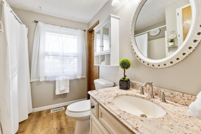 bathroom featuring hardwood / wood-style flooring, vanity, a textured ceiling, and toilet