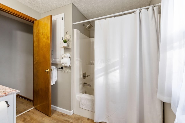 bathroom featuring vanity, hardwood / wood-style floors, shower / tub combo, and a textured ceiling