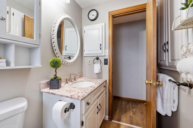 bathroom featuring vanity, toilet, wood-type flooring, and a textured ceiling