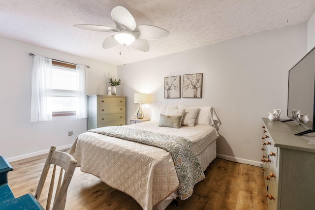 bedroom featuring ceiling fan, wood-type flooring, and a textured ceiling