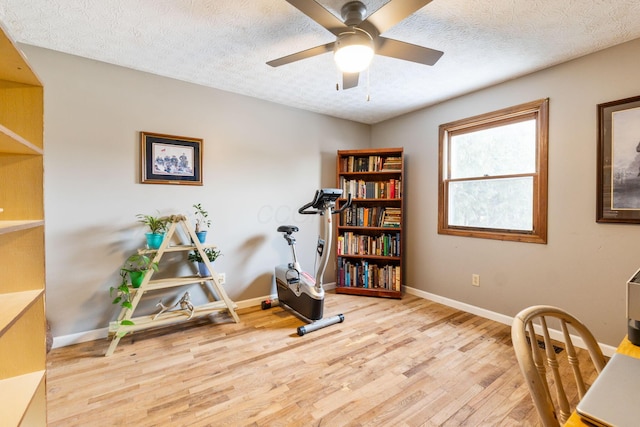 exercise area featuring hardwood / wood-style floors, a textured ceiling, and ceiling fan