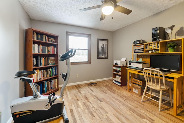 home office featuring ceiling fan, light hardwood / wood-style floors, and a textured ceiling