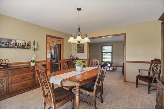 carpeted dining room featuring an inviting chandelier