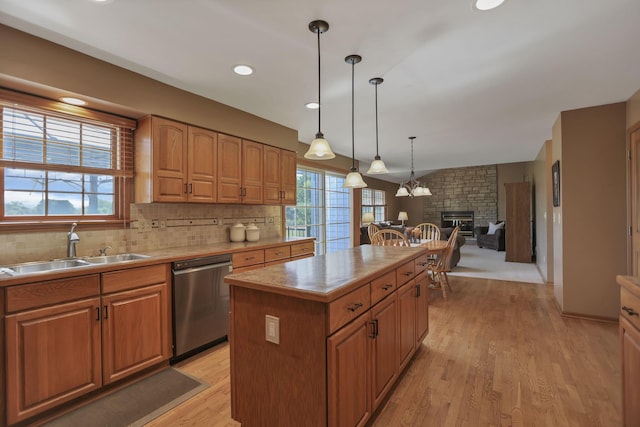 kitchen featuring stainless steel dishwasher, a kitchen island, light hardwood / wood-style floors, and a wealth of natural light