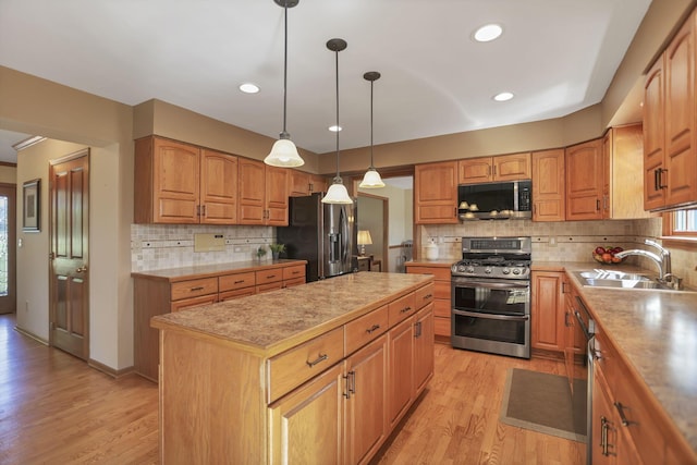 kitchen with backsplash, stainless steel appliances, sink, light hardwood / wood-style flooring, and a center island