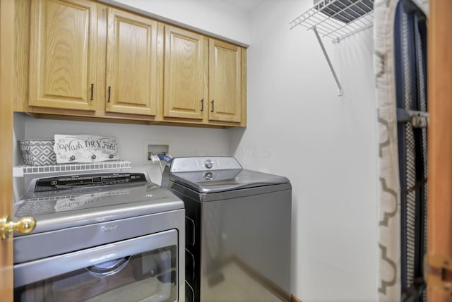 clothes washing area with washer and clothes dryer and cabinets