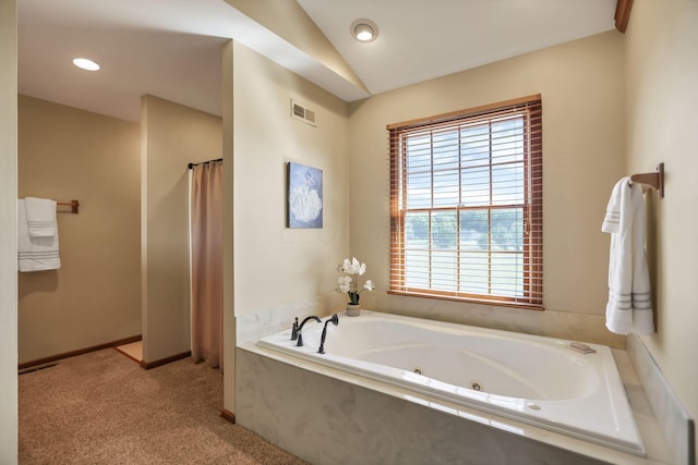 bathroom featuring a relaxing tiled tub and vaulted ceiling