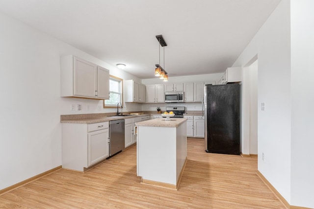 kitchen with white cabinetry, a center island, appliances with stainless steel finishes, pendant lighting, and light hardwood / wood-style floors