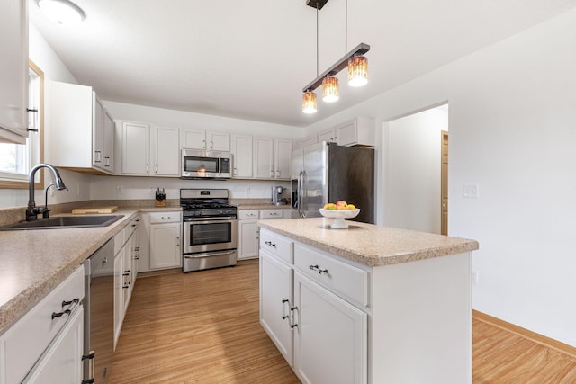 kitchen with a kitchen island, decorative light fixtures, white cabinetry, sink, and stainless steel appliances