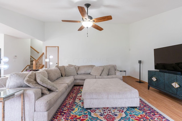 living room with hardwood / wood-style flooring, ceiling fan, and vaulted ceiling