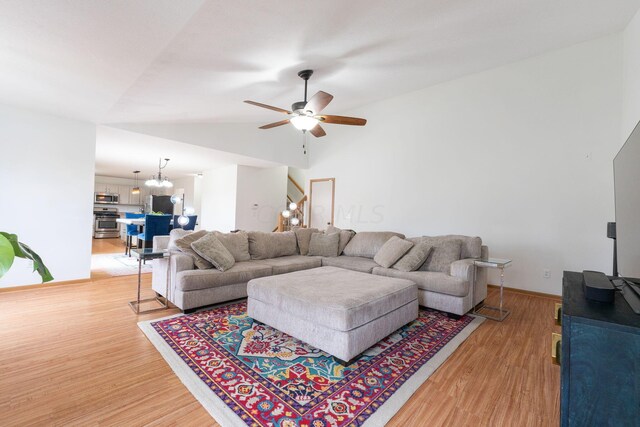 living room featuring hardwood / wood-style flooring, lofted ceiling, and ceiling fan with notable chandelier