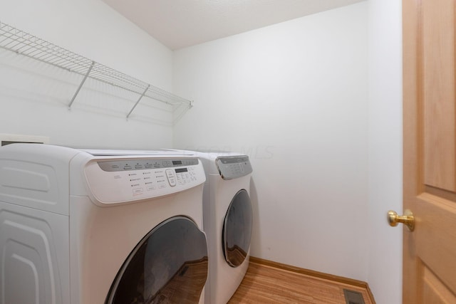 laundry room featuring separate washer and dryer and light hardwood / wood-style floors