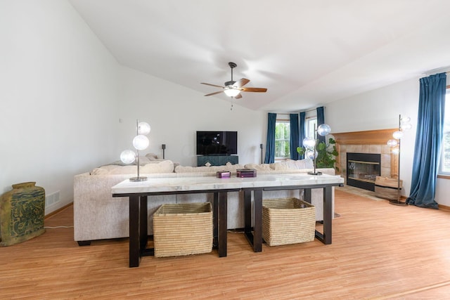 living room with vaulted ceiling, ceiling fan, a fireplace, and light wood-type flooring