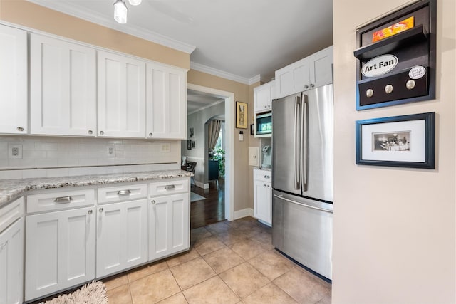 kitchen featuring crown molding, decorative backsplash, light tile patterned flooring, white cabinetry, and stainless steel appliances