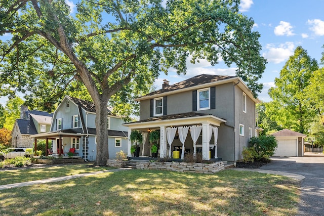 view of front of property featuring an outbuilding, covered porch, a front yard, and a garage