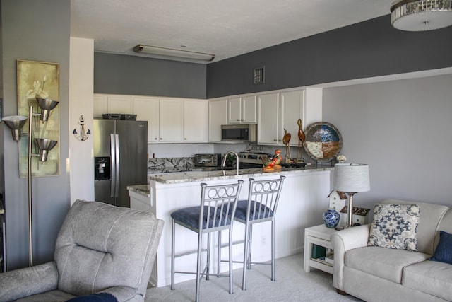 4401 Hunts Landing Rd Unit 202, Hebron, OH 43025 - kitchen with appliances with stainless steel finishes, open floor plan, light colored carpet, a peninsula, and white cabinets