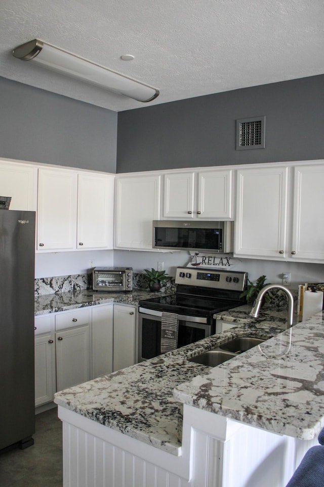 4401 Hunts Landing Rd Unit 202, Hebron, OH 43025 - kitchen featuring stainless steel appliances, a peninsula, white cabinetry, light stone counters, and a textured ceiling