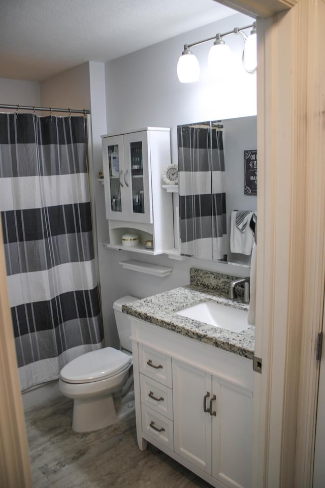 bathroom featuring a shower with curtain, vanity, a textured ceiling, wood-type flooring, and toilet