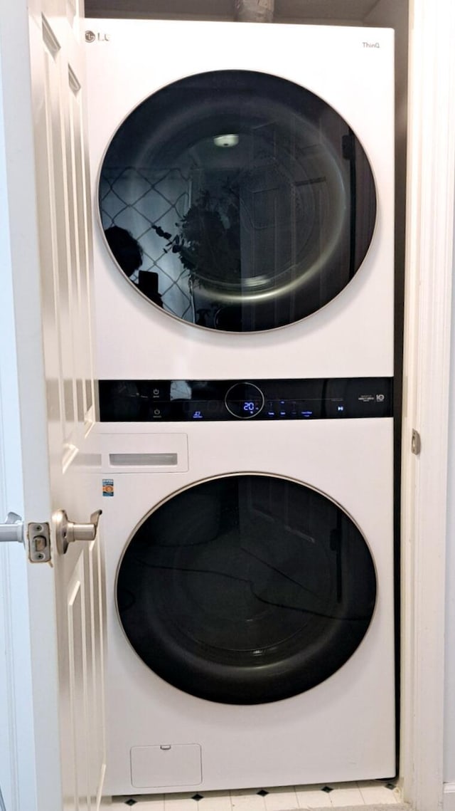 laundry area featuring light tile patterned flooring and stacked washer and dryer