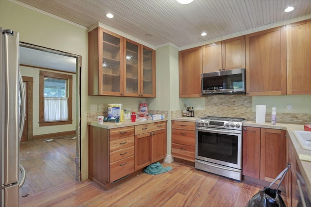 kitchen featuring decorative backsplash, appliances with stainless steel finishes, light hardwood / wood-style floors, and crown molding