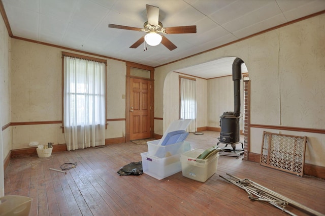 interior space with a wood stove, ceiling fan, and wood-type flooring