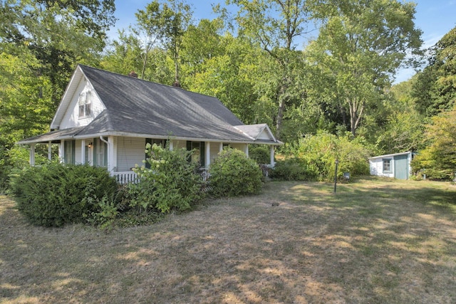 view of side of home featuring a lawn, a storage unit, and covered porch