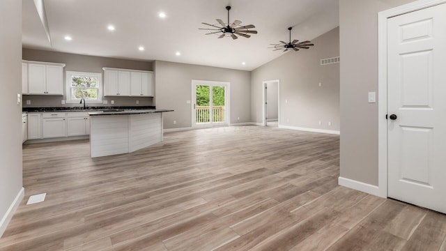 kitchen with white cabinetry, a center island, ceiling fan, and light hardwood / wood-style flooring