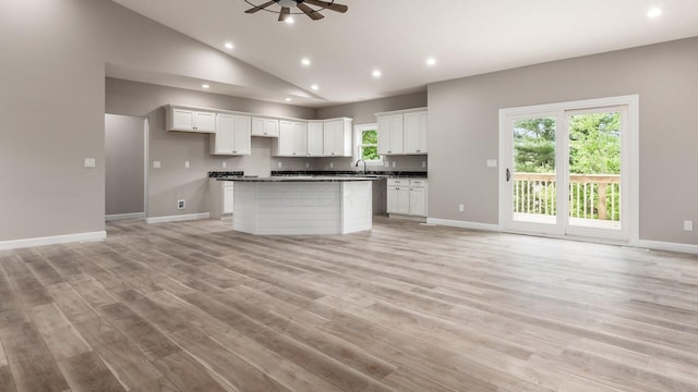 kitchen with ceiling fan, sink, a kitchen island, light hardwood / wood-style flooring, and white cabinets