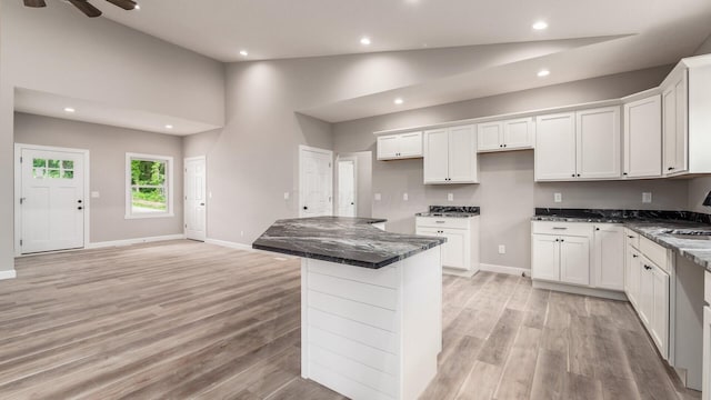 kitchen featuring ceiling fan, dark stone countertops, white cabinets, light hardwood / wood-style floors, and a kitchen island