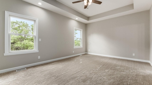 unfurnished room with a raised ceiling, ceiling fan, and carpet floors