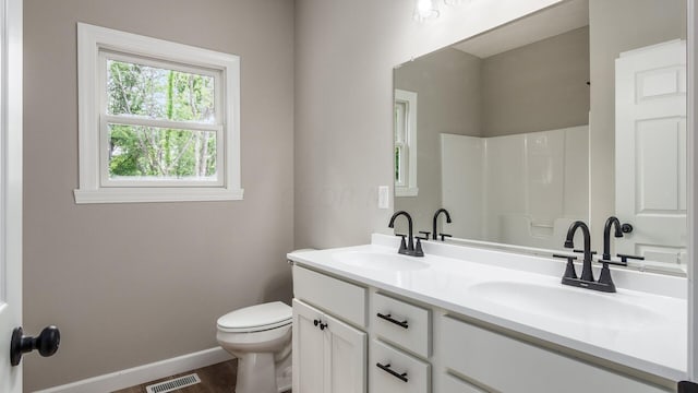 bathroom featuring vanity, toilet, and walk in shower