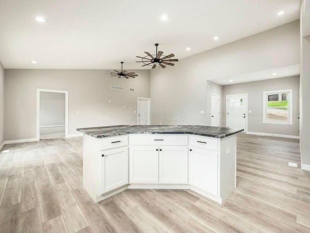 kitchen featuring white cabinets, a kitchen island, dark stone countertops, and light hardwood / wood-style flooring