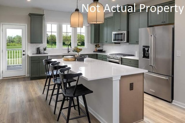 kitchen featuring light wood-style floors, light countertops, a kitchen bar, and high quality appliances