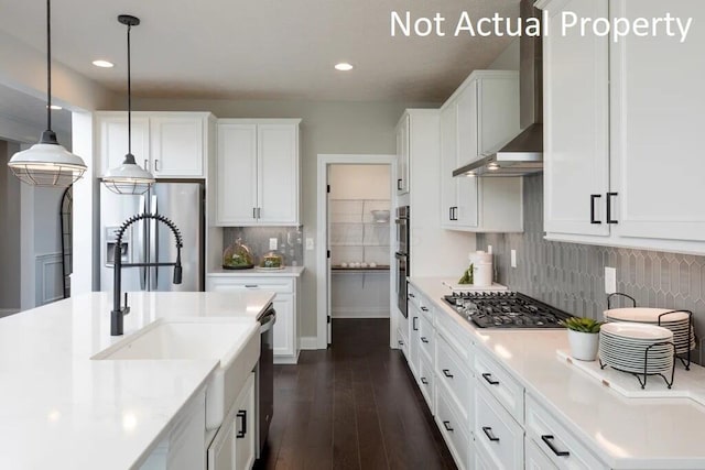 kitchen featuring wall chimney exhaust hood, stainless steel appliances, light countertops, and a sink