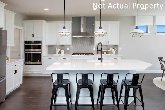 kitchen featuring recessed lighting, dark wood finished floors, stainless steel appliances, wall chimney exhaust hood, and decorative backsplash