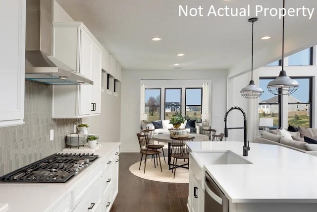 kitchen featuring tasteful backsplash, stainless steel appliances, light countertops, wall chimney exhaust hood, and dark wood-type flooring