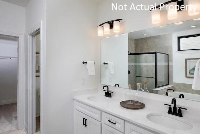 full bathroom with a walk in closet, double vanity, a stall shower, and a sink