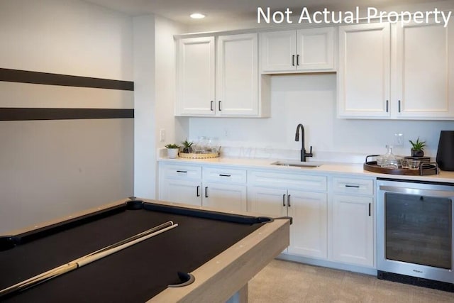 kitchen with white cabinets, a sink, wine cooler, and light countertops