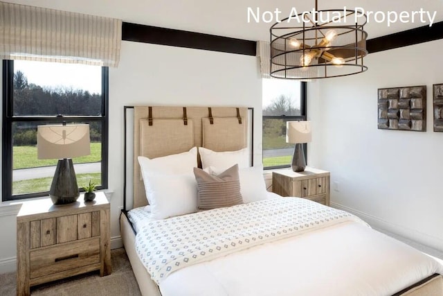 carpeted bedroom with baseboards, a notable chandelier, and multiple windows