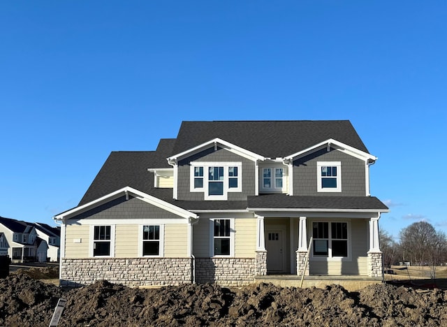 craftsman inspired home featuring stone siding, a shingled roof, and a porch