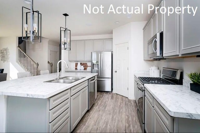 kitchen featuring appliances with stainless steel finishes, sink, gray cabinetry, a kitchen island with sink, and light hardwood / wood-style floors