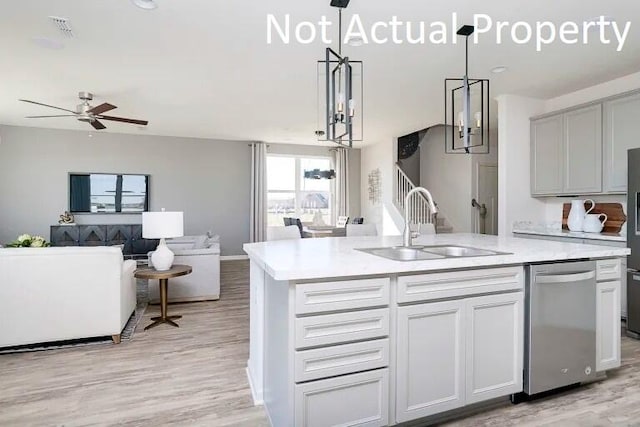 kitchen with sink, stainless steel dishwasher, an island with sink, pendant lighting, and light hardwood / wood-style floors